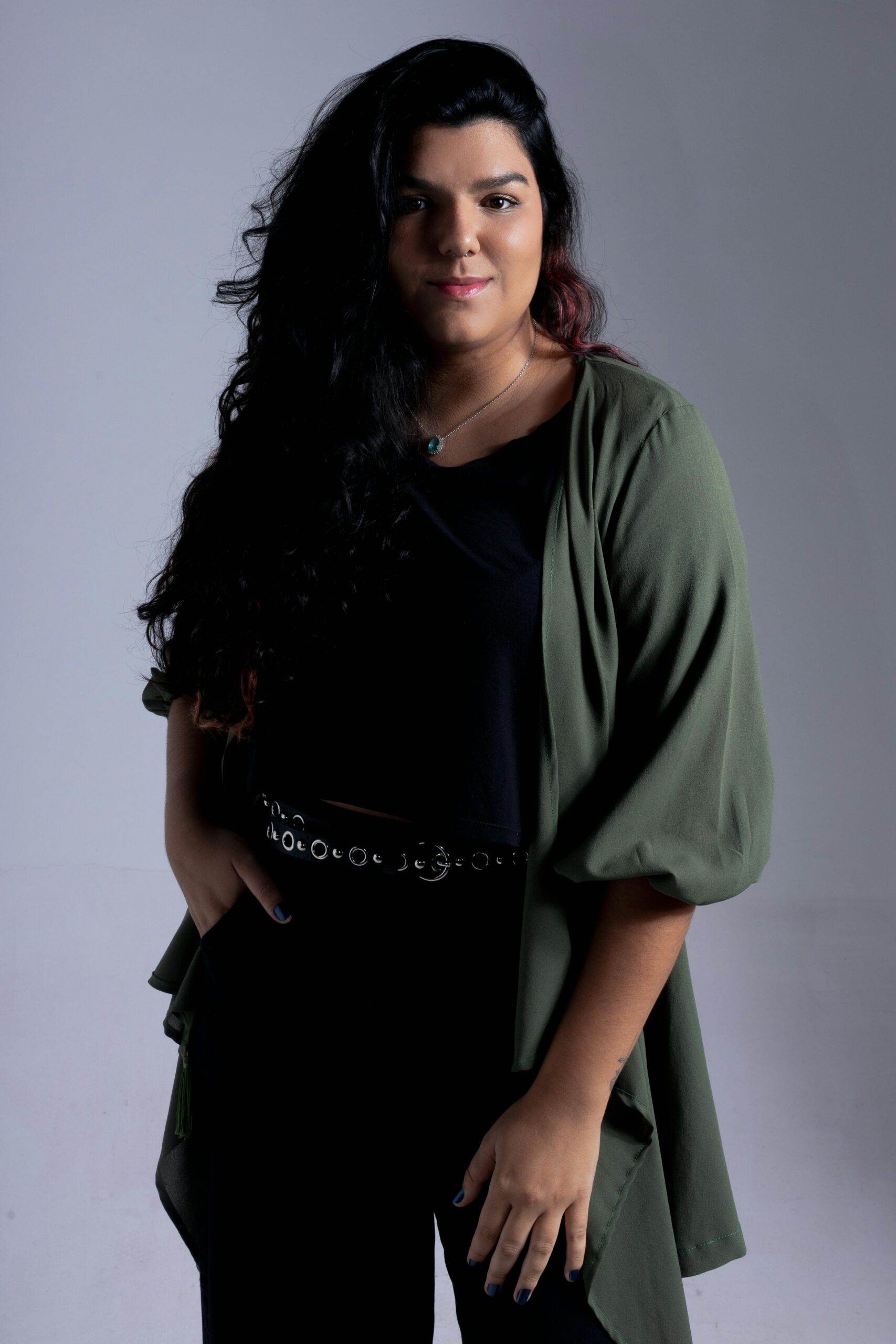 Fashionable portrait of a young woman in a studio setting with a green jacket, exuding confidence.